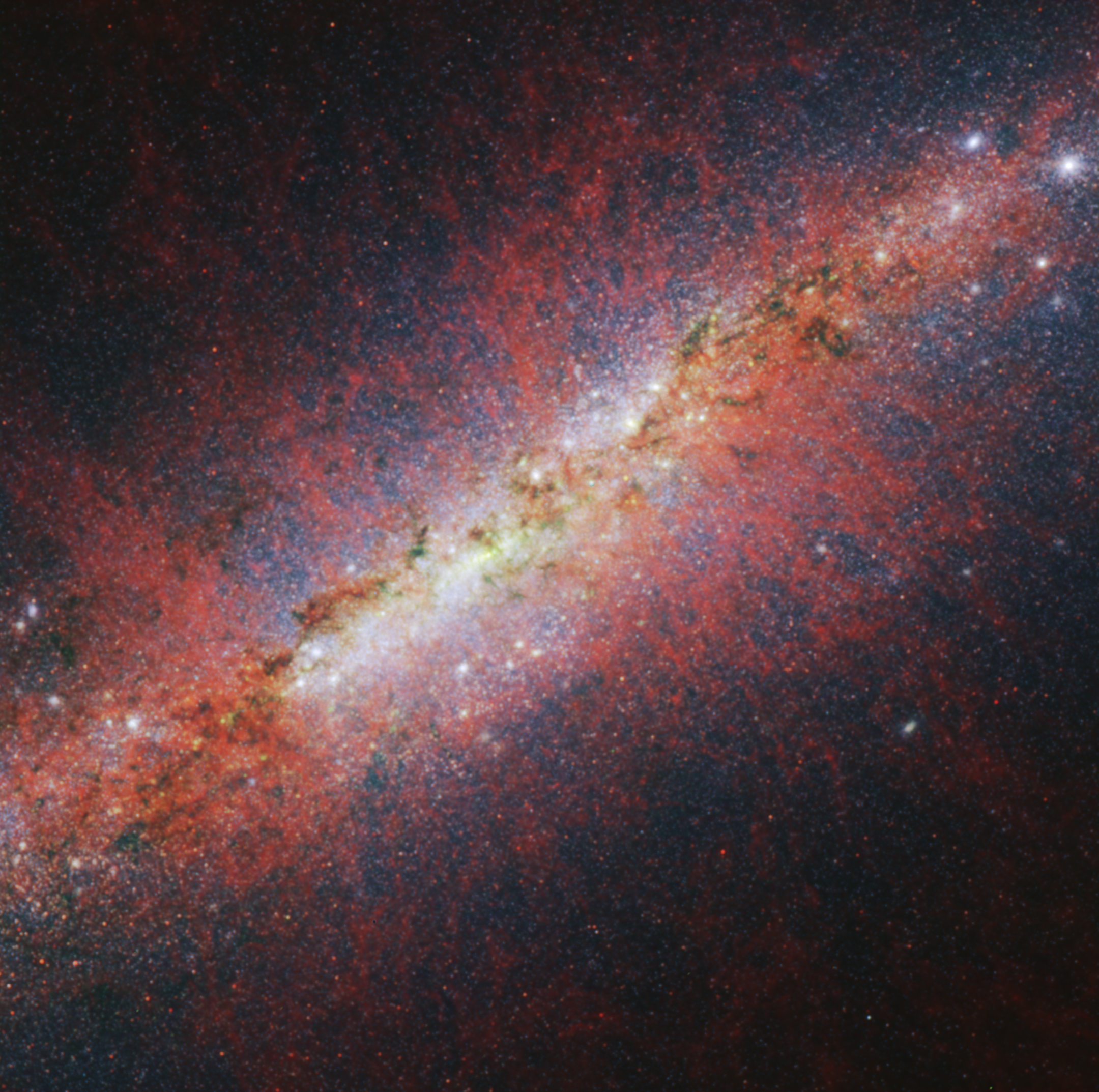 Na ilustracji: centralny obszar galaktyki M82 (Galaktyka Cygaro), w której zachodzą procesy gwiazdotwórcze o 10-krotnie większym tempem niż w Drodze Mlecznej. Zdjęcie uzyskane za pomocą kamery NIRCAM i Teleskopu Webba w zakresie długości fali λλ=1,64-3,35μm prezentuje emisje wielopierścieniowych węglowodorów aromatycznych (PAH), które śledzą strukturę wiatru gwiazdowego M82. PAH są złożonymi molekułami i/lub bardzo drobnymi ziarnami pyłu, które są niszczone w wysokich temperaturach. Nieoczekiwanie struktura tych emisji jest podobna do rozkładu gorącego i zjonizowanego gazu – co sugeruje, że PAH może być uzupełniana przez ciągłą jonizację molekuł gazu. Na zdjęciu barwom czerwona/zielona/niebieska odpowiadają długości fali λλ=3,35/2,50/1,64 μm. Źródło: NASA, ESA, CSA, STScI, A. Bolatto (University of Maryland)