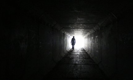 Kobieca postać na końcu długiego, ciemnego tunelu.